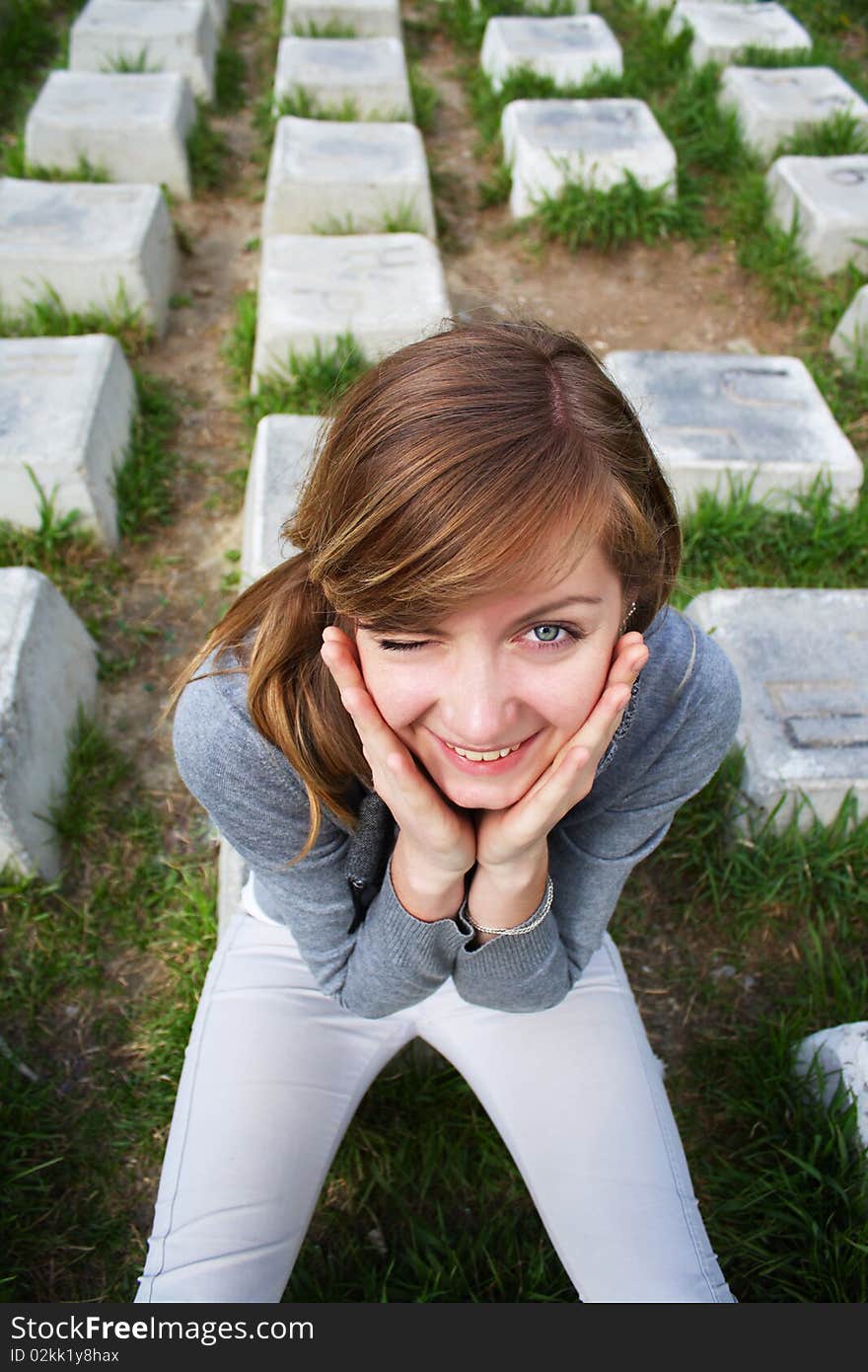 The young cheerful girl sits on a stone. The young cheerful girl sits on a stone