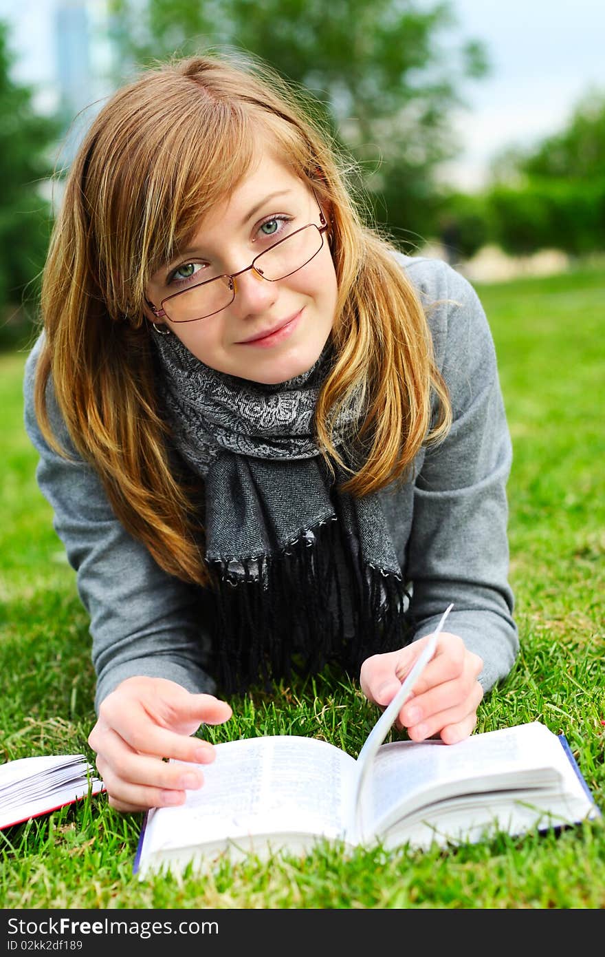 The girl lays on a green grass, and reads the book. The girl lays on a green grass, and reads the book