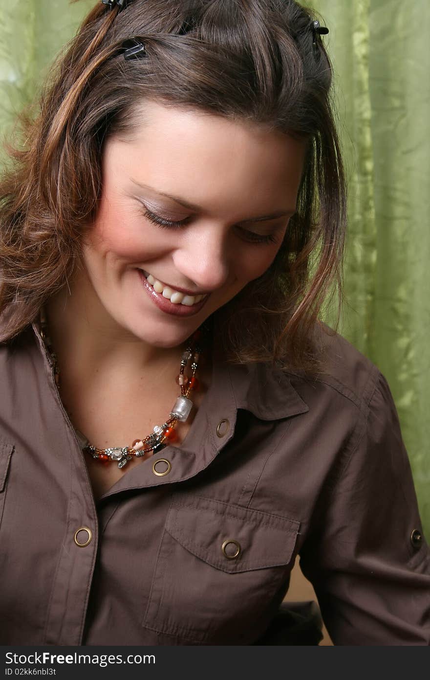 Beautiful brunette female wearing a brown shirt against a green background. Beautiful brunette female wearing a brown shirt against a green background