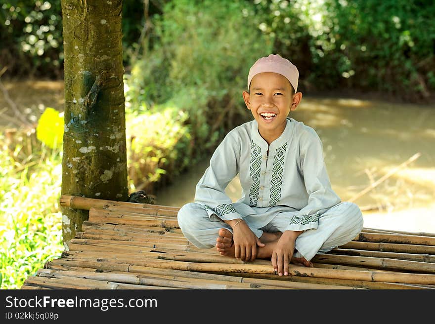 Happy Muslim boy sitting by the pond. Happy Muslim boy sitting by the pond