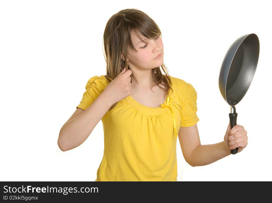 Girl looks in reflexion at bottom of frying pan isolated in white