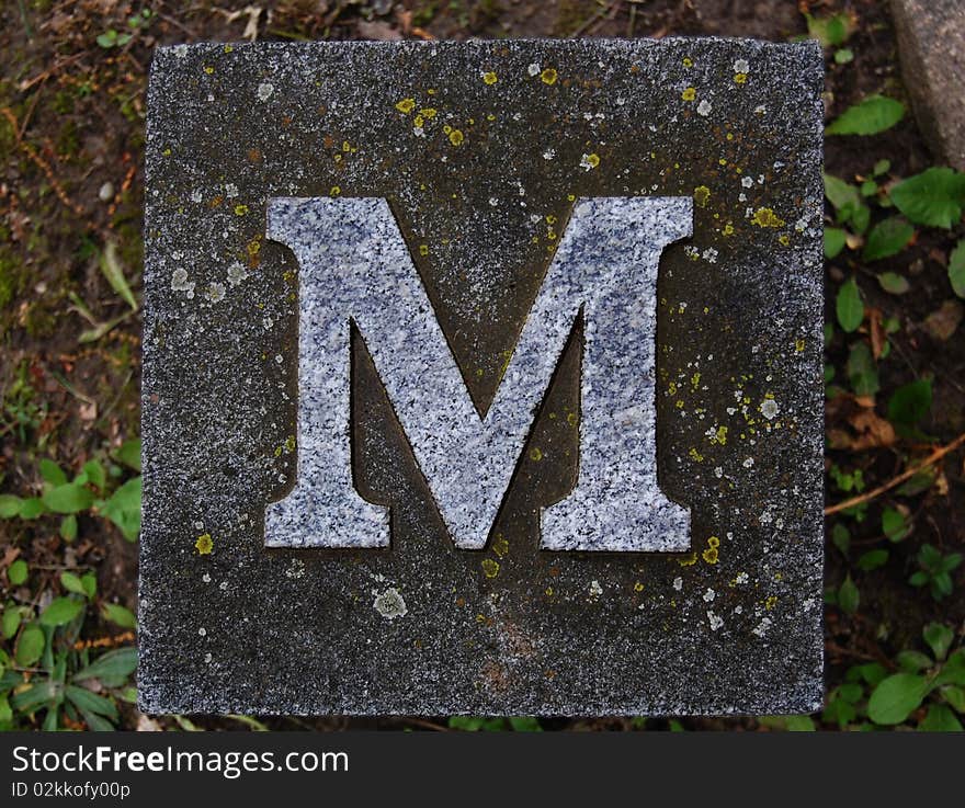 Block with letter M stone, in ground. Block with letter M stone, in ground