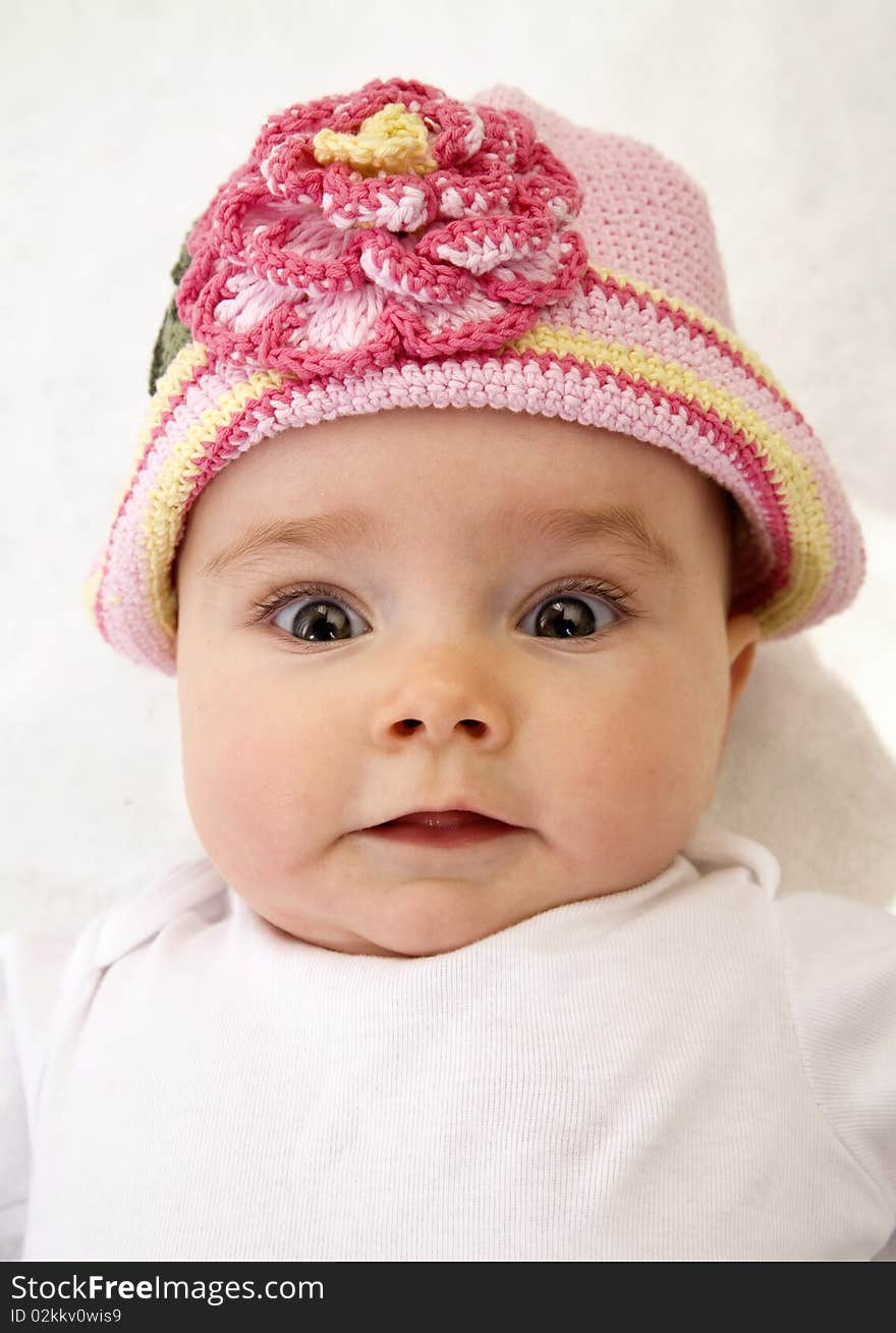 A close up of an infant wearing a pink hat  with a surprised look on her face. A close up of an infant wearing a pink hat  with a surprised look on her face.