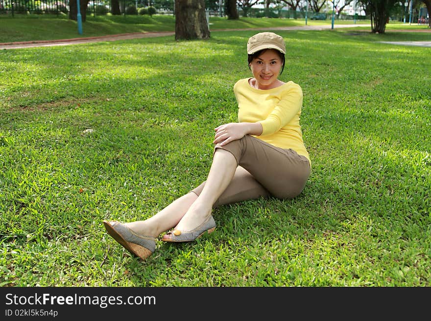 Young woman enjoying sunshine on green grass in park . Young woman enjoying sunshine on green grass in park