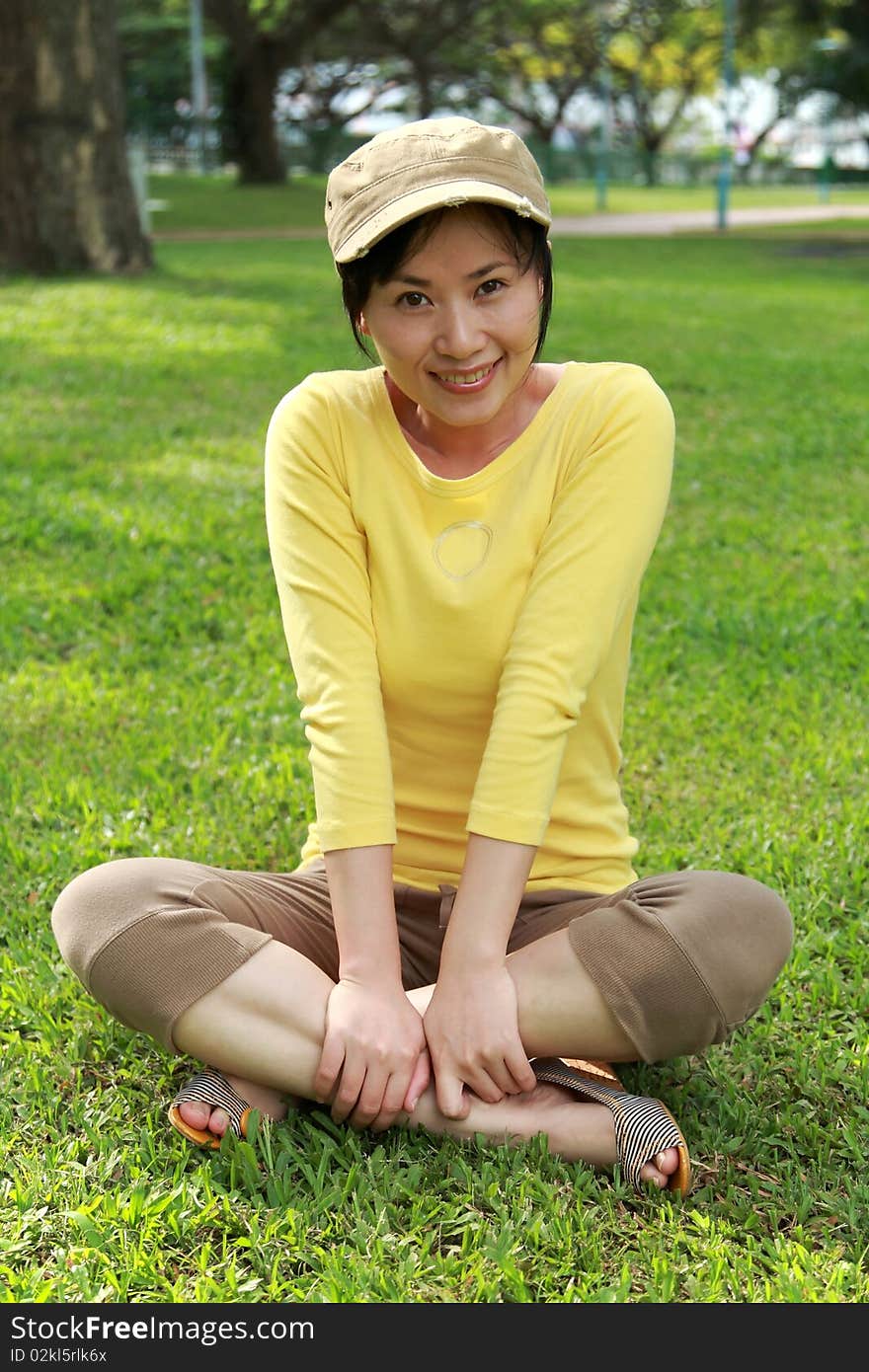 Young woman enjoying sunshine on green grass in park.Singapore. Young woman enjoying sunshine on green grass in park.Singapore