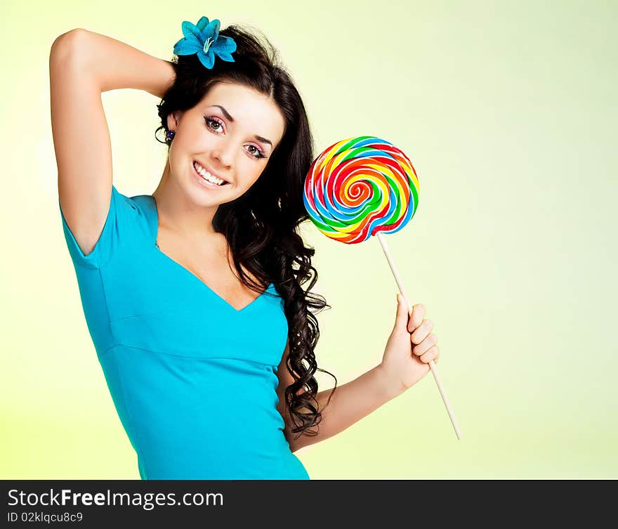 Pretty smiling brunette girl with a lollipop in her hand