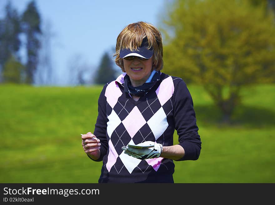 Woman at the golf range writing down the score handicap. Woman at the golf range writing down the score handicap.