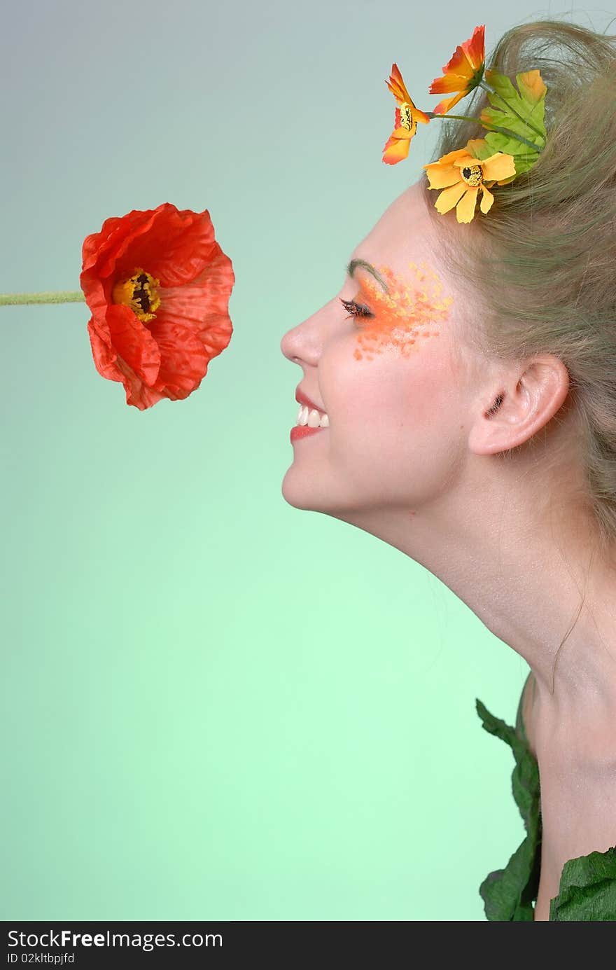 Portrait of forest nymph sniffing poppy