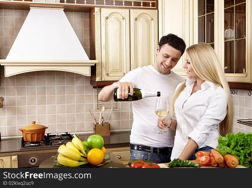 The young man pours champagne to the girl on kitchen. The young man pours champagne to the girl on kitchen