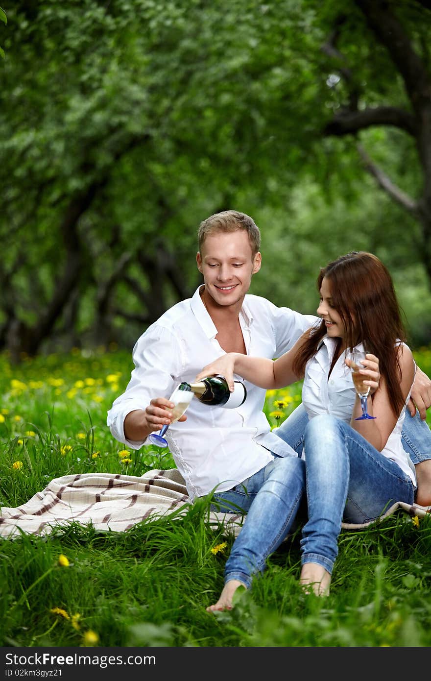 The attractive enamoured couple drinks champagne in park. The attractive enamoured couple drinks champagne in park