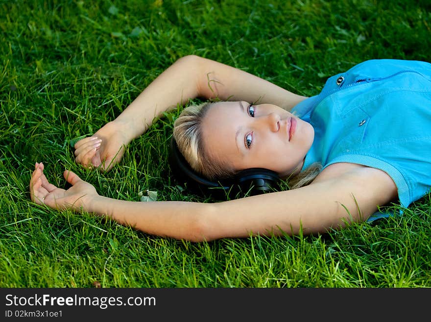 Girl listening music on headphones, on grass