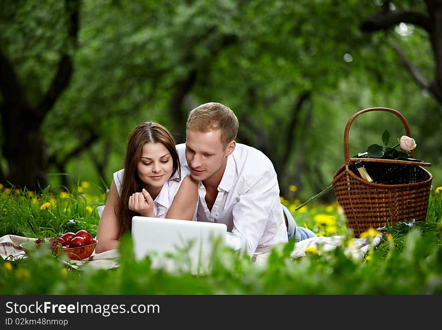 Young people look in the laptop monitor in park