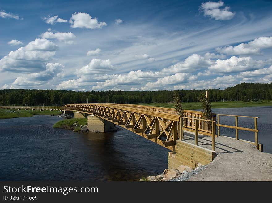 Wooden bridge across the river under impressive sky. Wooden bridge across the river under impressive sky