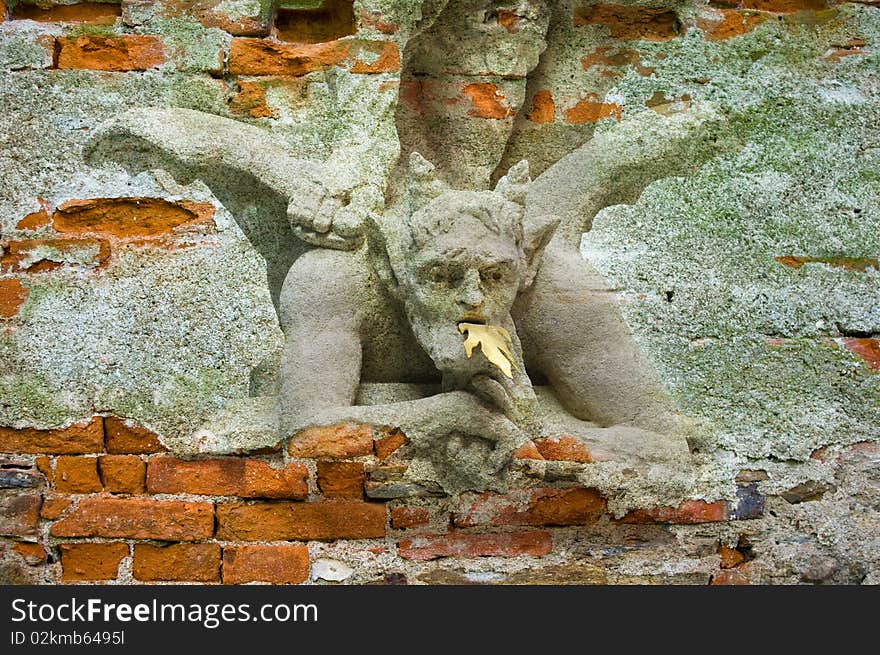 Devil under foot of st. Michael. An old bricks wall with picture.