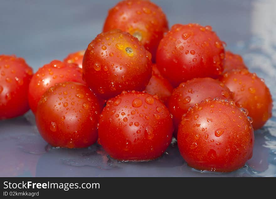 Bunch of cherry tomato on a blue wet background