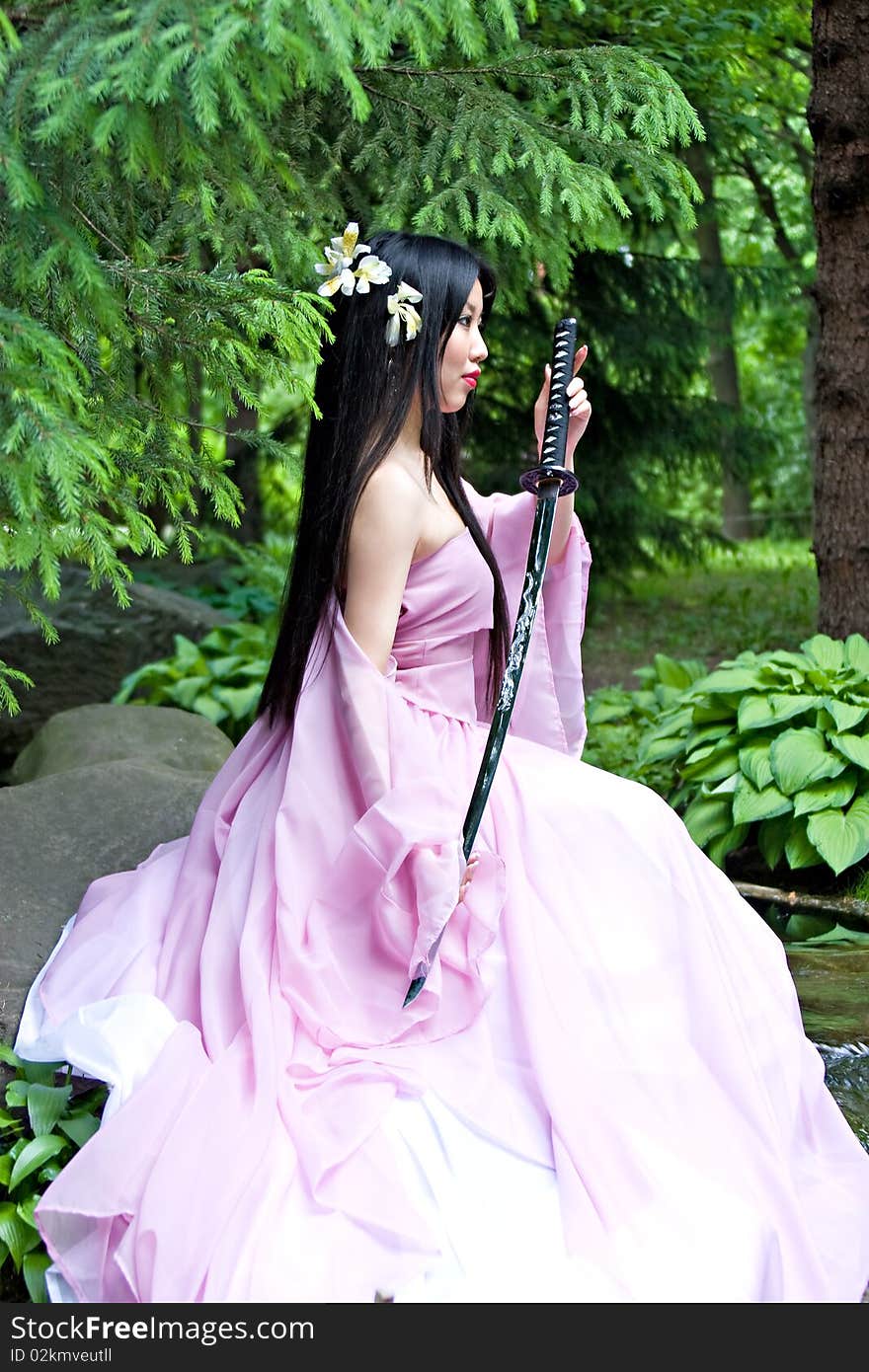 Beutiful japanese woman in pink dress wields a sword