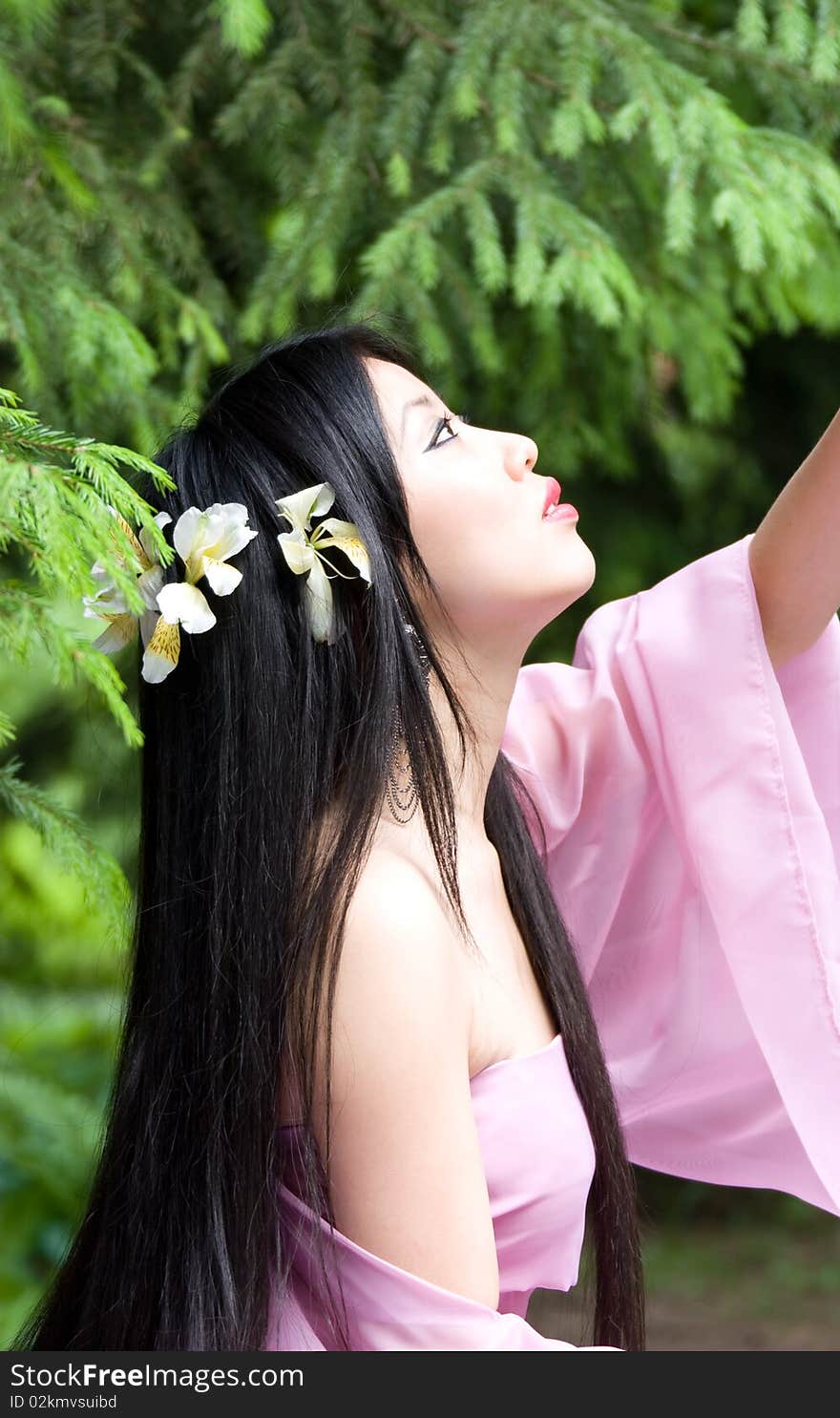 Beautiful asian woman in a pink dress with flowers in her hair. Beautiful asian woman in a pink dress with flowers in her hair