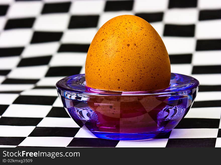 Egg on a transparent stand at the checkered background