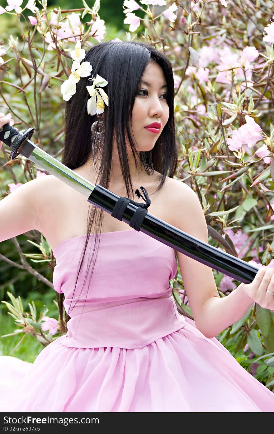 Beutiful japanese woman in pink dress wields a sword