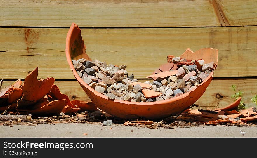 Broken flower pot discarded next to wooden retaining wall. Broken flower pot discarded next to wooden retaining wall