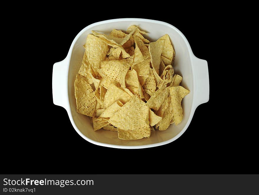 Corn tortilla chips contained in a white bowl isolated on black background. Corn tortilla chips contained in a white bowl isolated on black background.