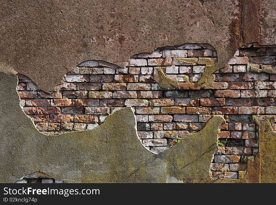 Old worn out brick wall with plaster partly covering them up.