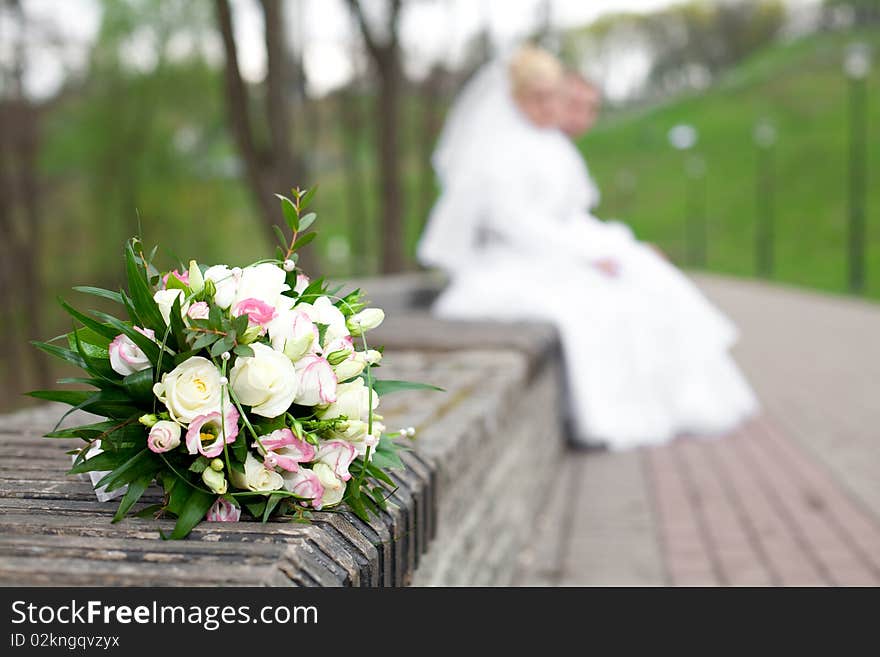 Wedding bouquet in the foreground, the background newlyweds