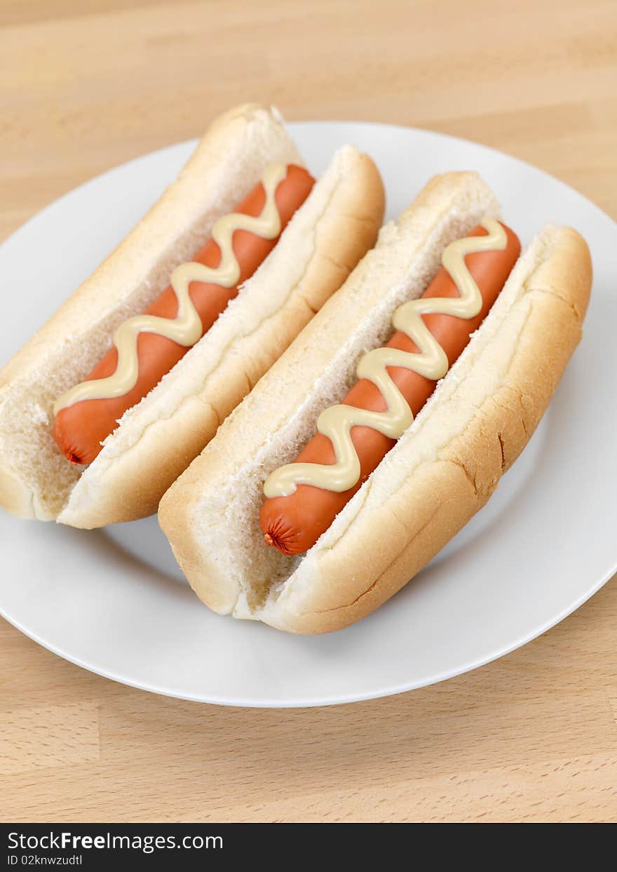 A hotdog with mustard sauce on a kitchen bench. A hotdog with mustard sauce on a kitchen bench