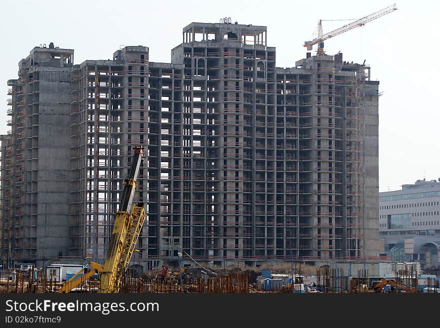 Building crane at the background of a multi-storey building under construction