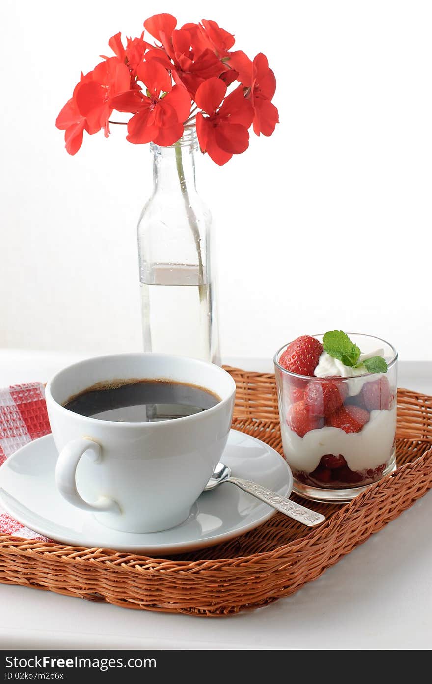 Wicker tray with breakfast of coffee and strawberry dessert