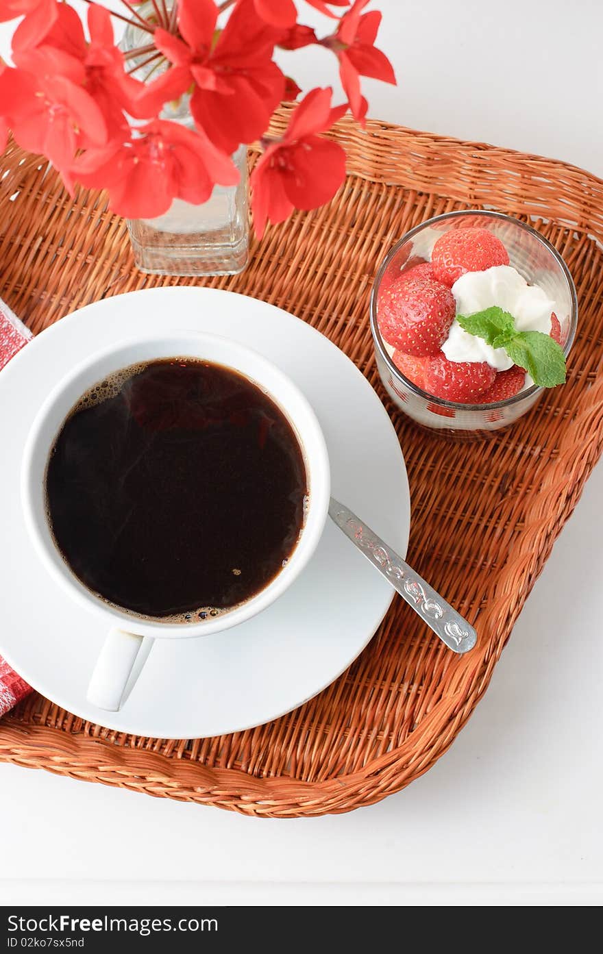 Wicker tray with breakfast of coffee and strawberry dessert