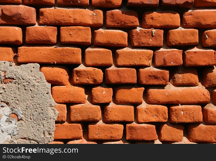 Fragment of an old wall with the rests of plaster and bricks at which from a rain and a wind sides were erased