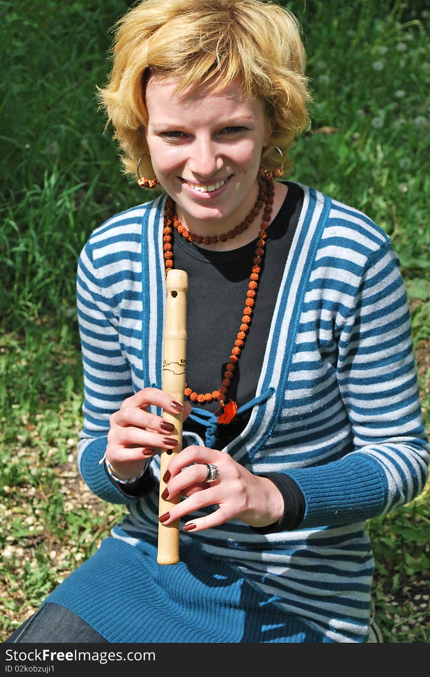 Young blond woman with wooden reed outdoor. Young blond woman with wooden reed outdoor