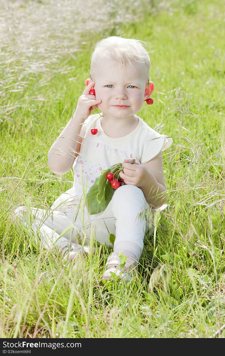 Little girl with cherries sitting on grass. Little girl with cherries sitting on grass