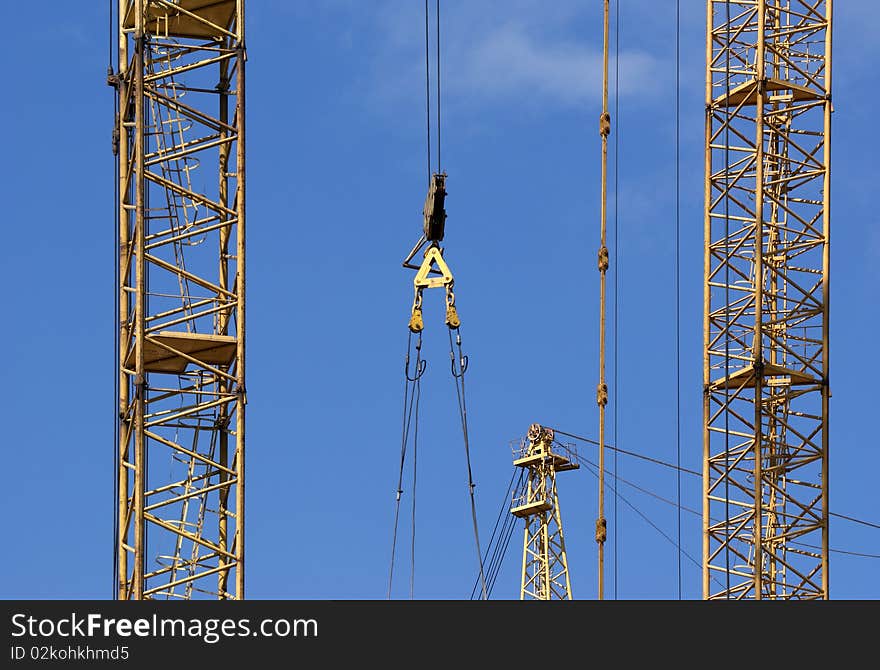 Elevating construction crane against the blue sky in a fair weather