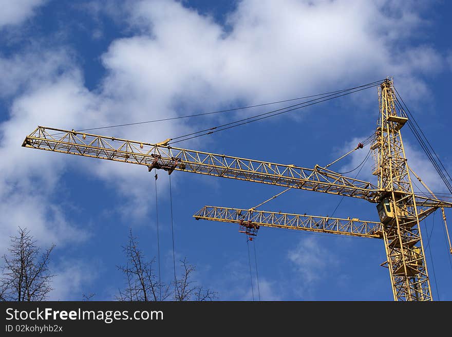 Elevating construction crane against the blue sky in a fair weather