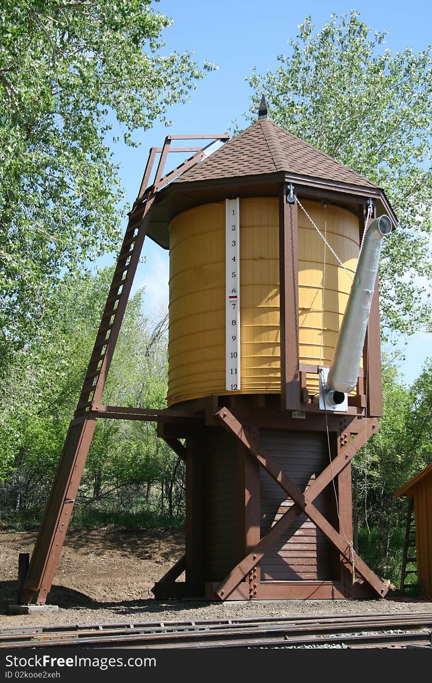 An old water tower stands next to the train tracks