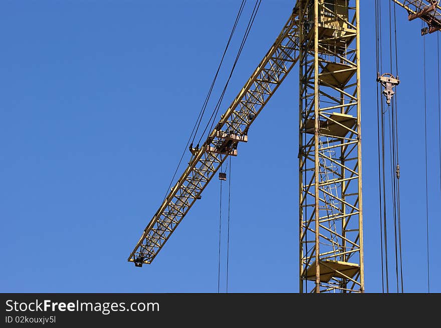 Elevating construction crane against the blue sky in a fair weather