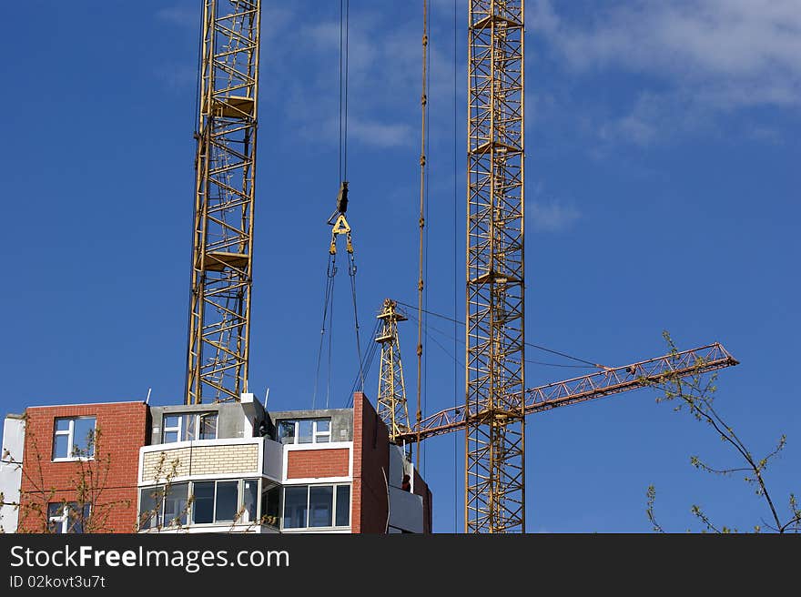 Elevating construction crane against the blue sky in a fair weather