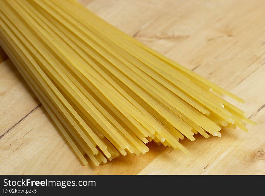 Wisp of raw spaghetti over wooden desk macro shot