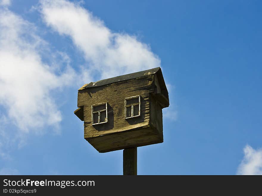 Old wooden birdhouse over blue sky