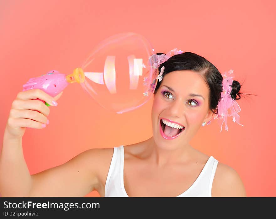 Beautiful happy teenage girl blowing soap bubbles and havinh fun. pink background