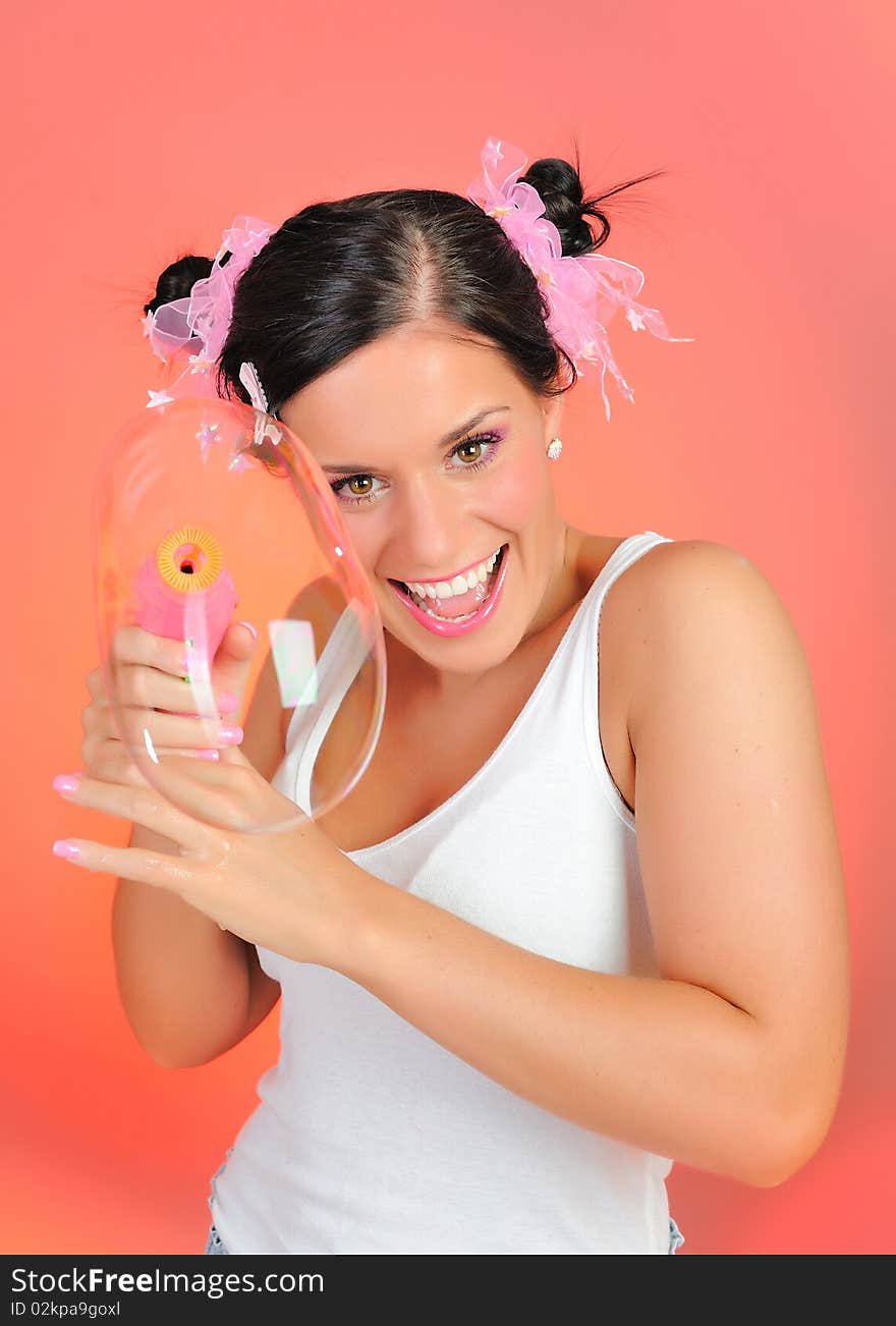 Beautiful happy teenage girl blowing soap bubbles and havinh fun. pink background