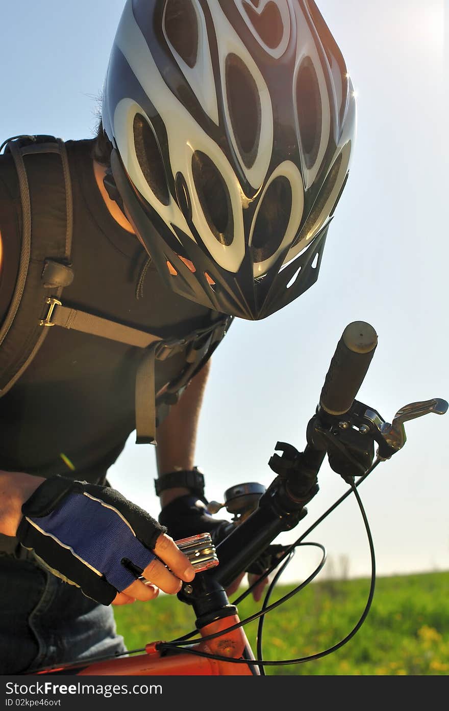 A cyclist tightening handlebars of the bike in the field. A cyclist tightening handlebars of the bike in the field