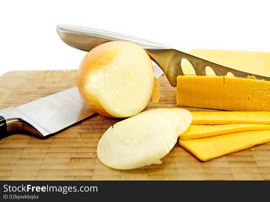 Sliced Yellow Cheese and Brown Onion with knives / knife on a wooden cutting board. Sliced Yellow Cheese and Brown Onion with knives / knife on a wooden cutting board