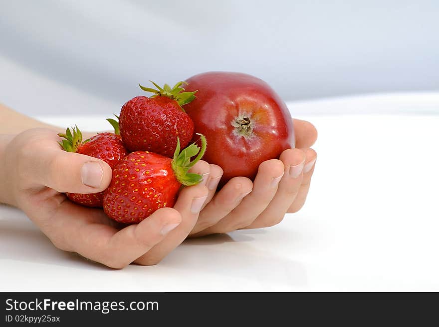 Child holds in the hands apple and strawberries. Child holds in the hands apple and strawberries