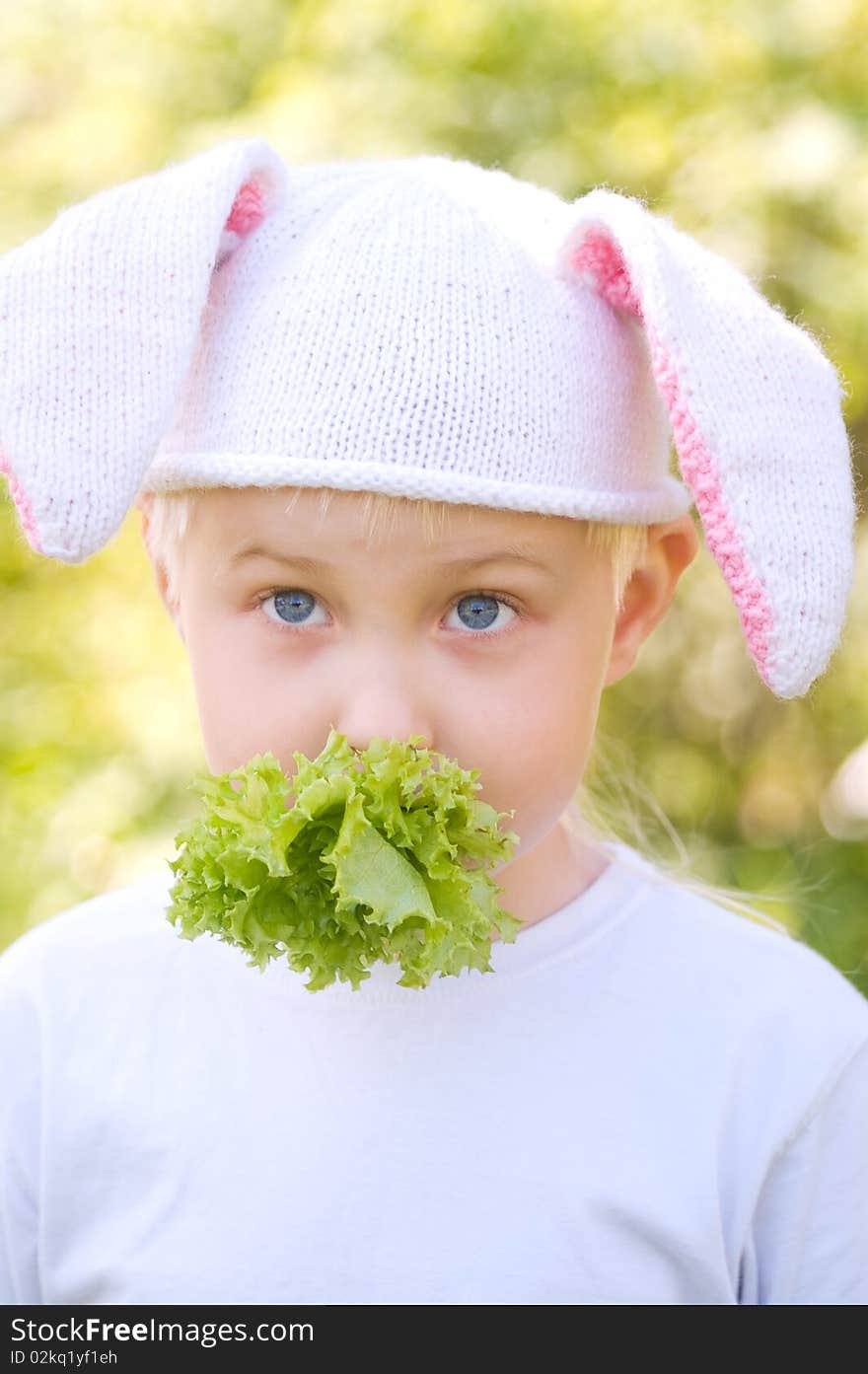 Portrait of the little boy in a cap with bunny ears and eating lettuce. Portrait of the little boy in a cap with bunny ears and eating lettuce