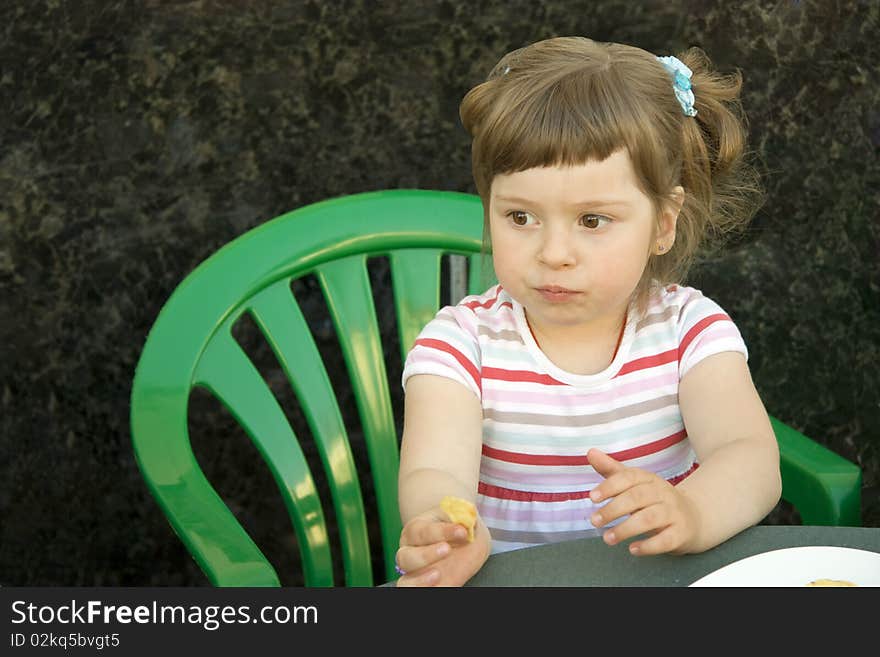 The girl in a striped dress sits at a table with chips and has reflected