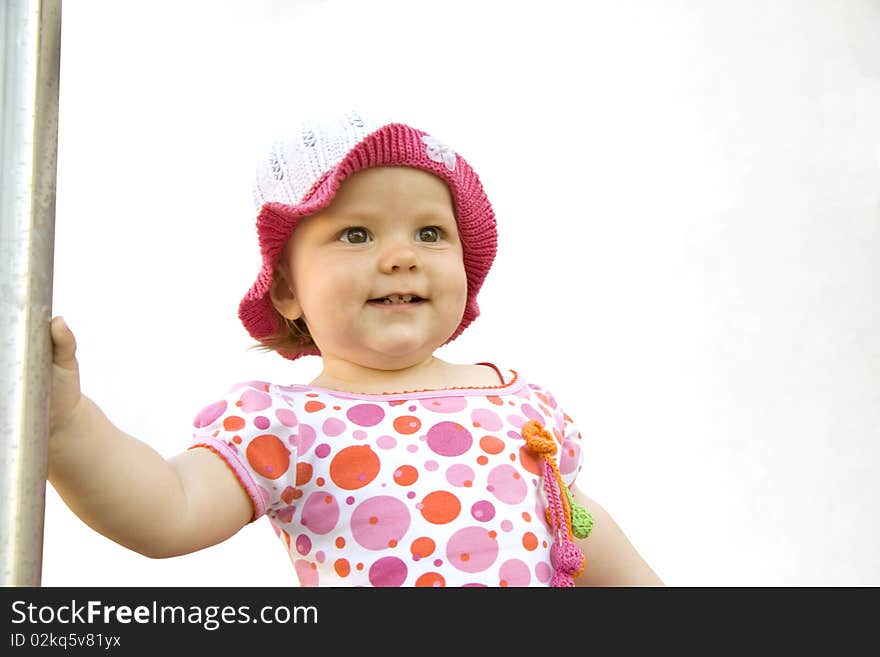 The joyful little girl in a dress and a hat looks forward. The joyful little girl in a dress and a hat looks forward