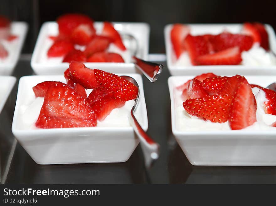 Fresh strawberries with whipped cream in dishes on the table